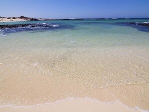 Een strand met helder ondiep water en een zandstrand.