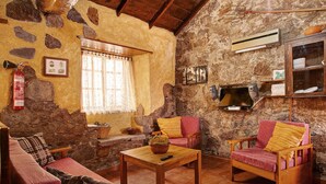 A rustic living room with stone walls, a wooden ceiling, a fireplace, a sofa, two armchairs, and a coffee table. - Rural House Pepita La De Las Flores (Tejeda)
