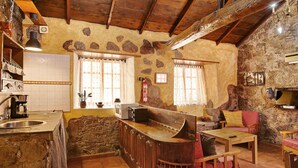 A rustic kitchen with stone walls, wooden beams, a built-in bar, and a stone sink. - Rural House Pepita La De Las Flores (Tejeda)