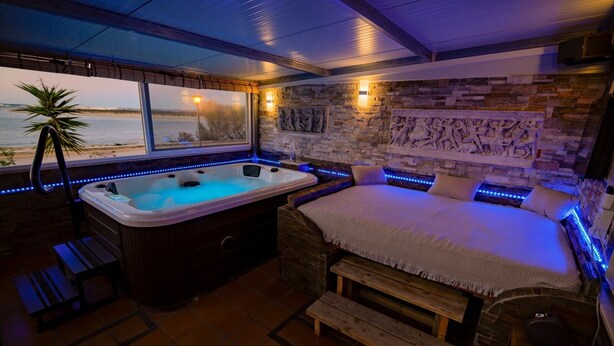 A room with a hot tub, a bed, and a view of the water. - Oceanum Visum Spa Deluxe (Puerto Real)