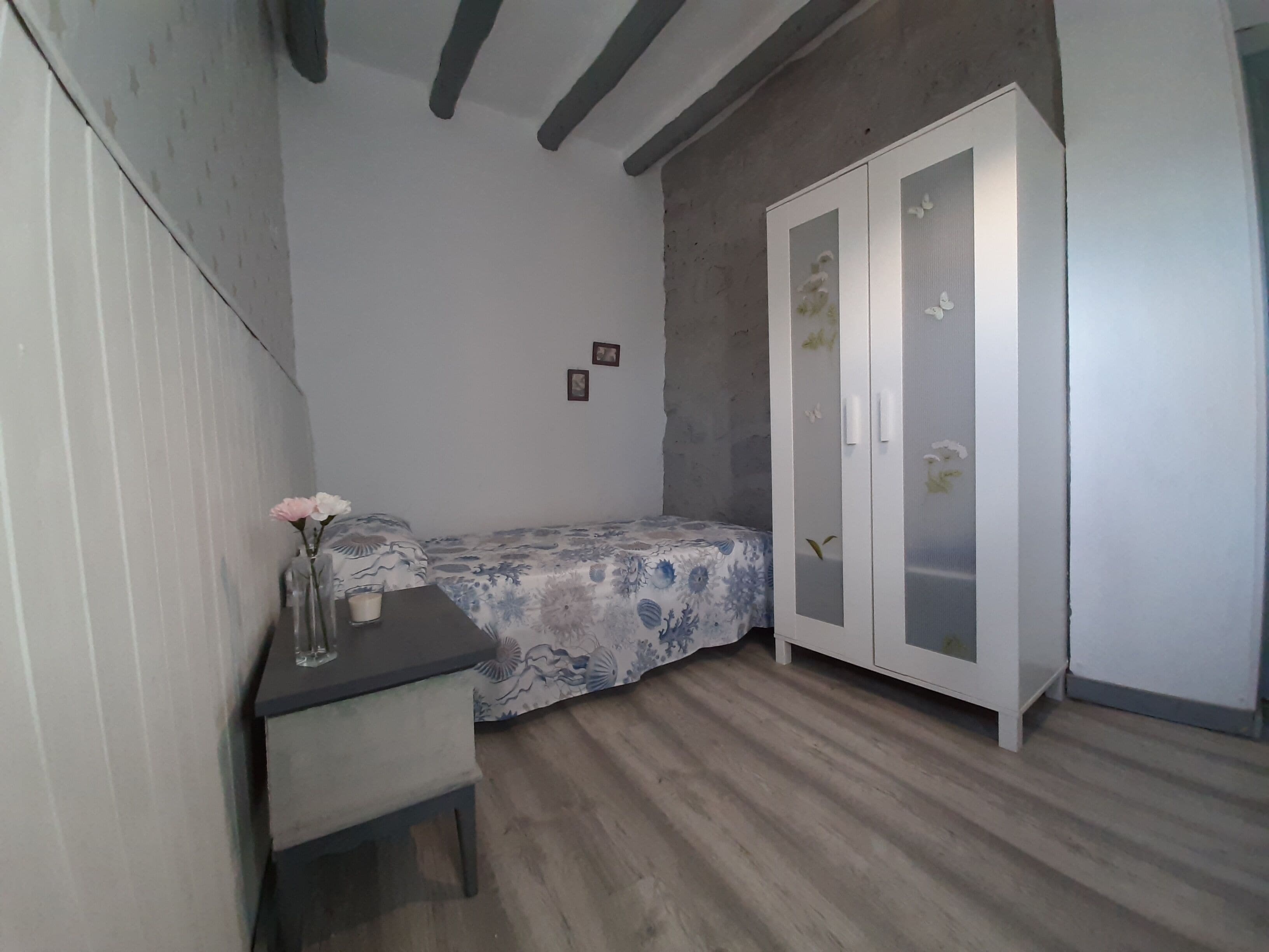A small bedroom with a bed, a desk, and a wardrobe.