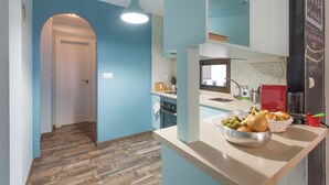 A kitchen with a wooden floor, a sink, a red coffee machine, and a bowl of fruit on the counter. - Sky is Blue in Granada (Granada)