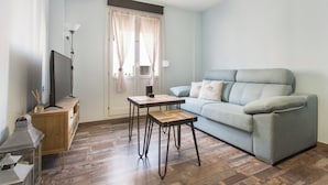 A modern living room with a grey sofa, a small wooden table, and a TV on a wooden cabinet. - Sky is Blue in Granada (Granada)