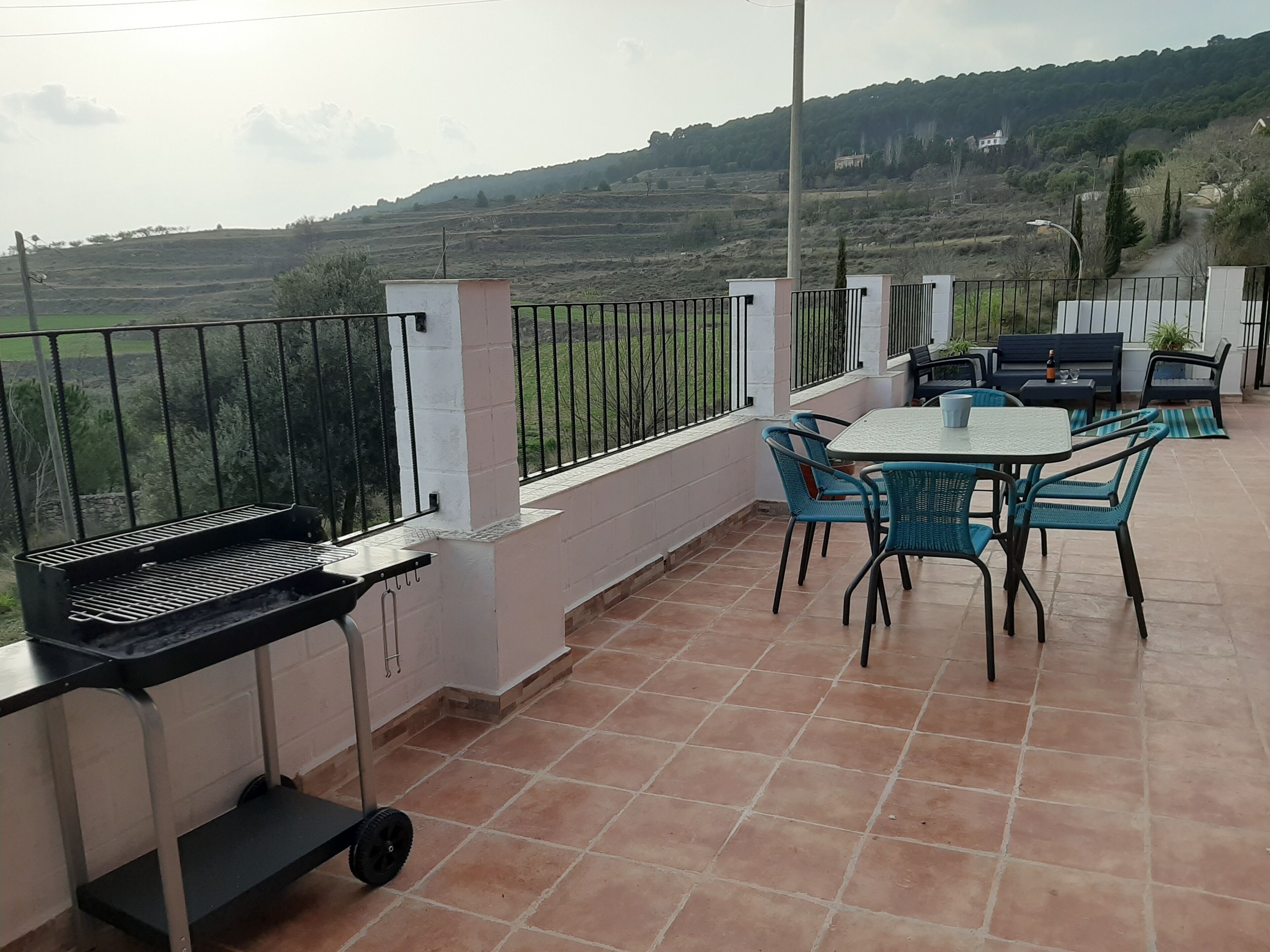 Una terrazza con barbecue, tavolo, sedie e vista sulla campagna.
