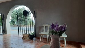 A room with a tiled floor, a white chair, a vase with purple flowers, and a door with a metal gate leading outside. - Casa Rural Garnacha de Borja has a Barbacue and Terrace (Borja)