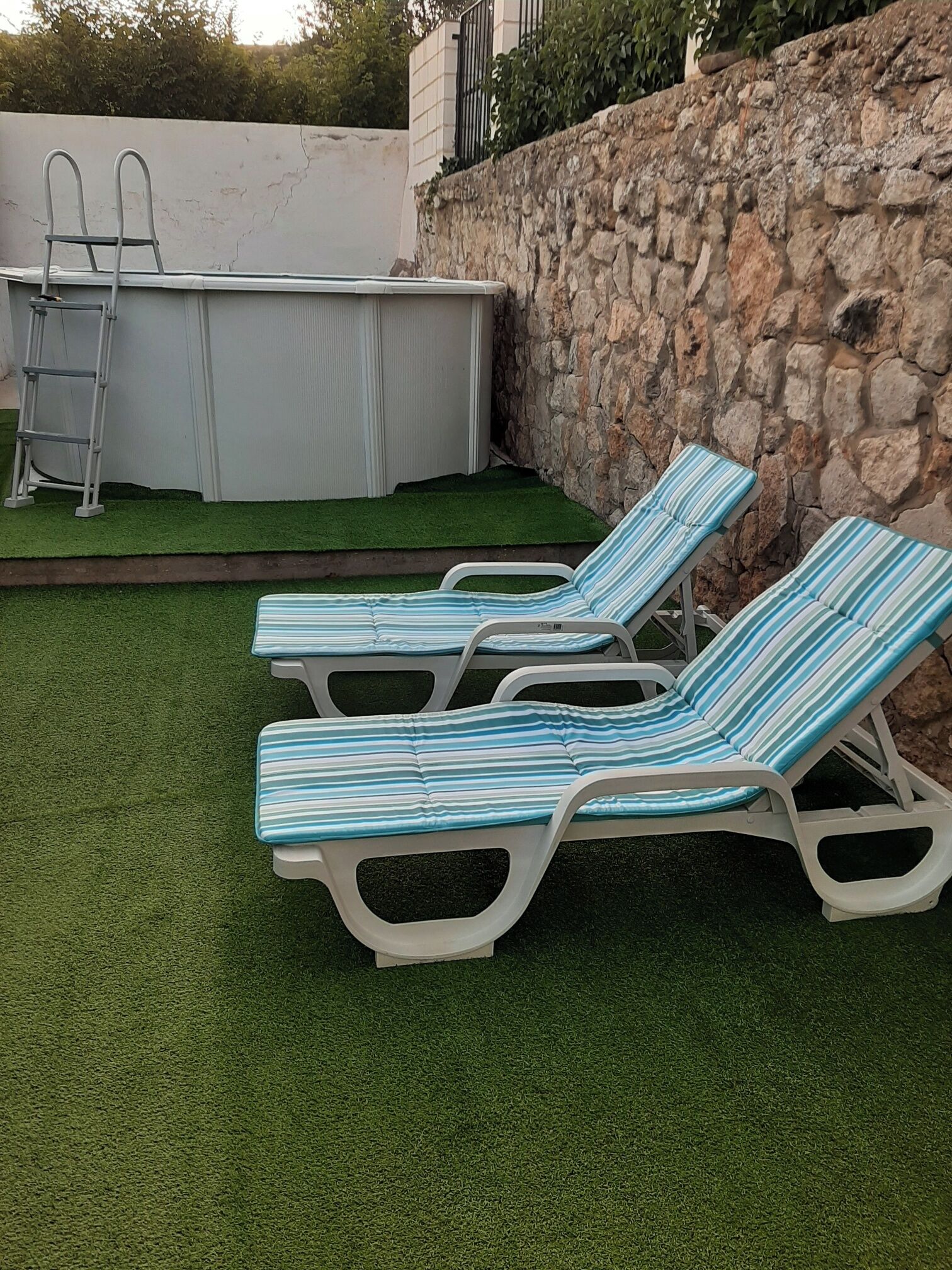 Un espace piscine équipé de deux chaises longues et d’une échelle.