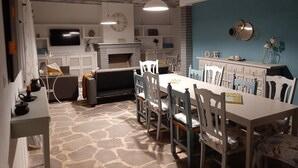 A dining area with a stone floor, white furniture, a fireplace, and a blue accent wall. - Casa Rural Garnacha de Borja has a Barbacue and Terrace (Borja)