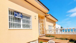 A patio with a round table and chairs, a tiled floor, and a building with a sign. - Beachfront Home La Mata (Torrevieja)