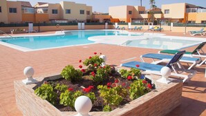 Una piscina con sillones de descanso y un parterre floral.
