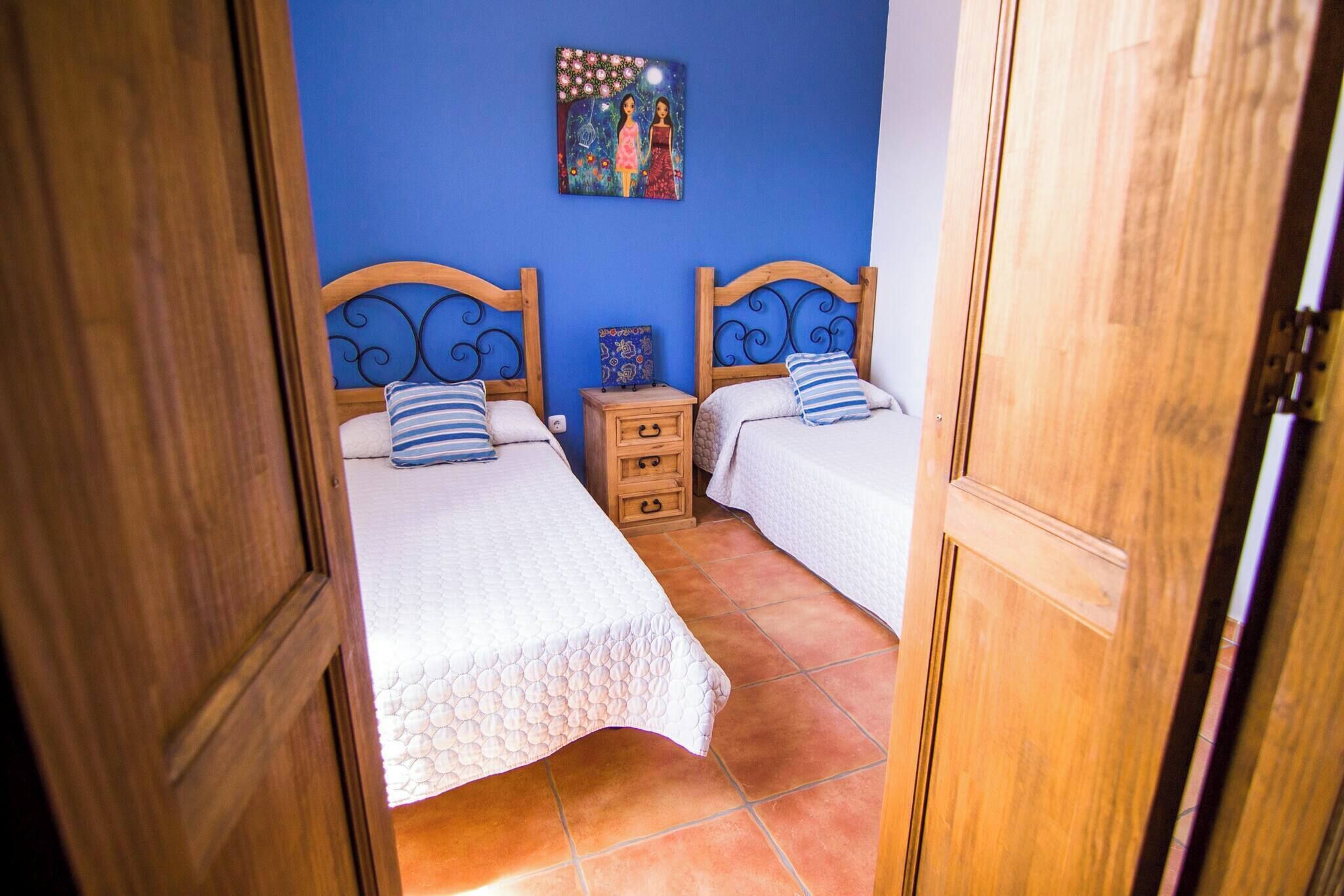 A bedroom with two beds, a wooden headboard, a nightstand, and a painting on the wall.