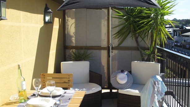 A balcony with a table set for two, a bottle of wine, and a fan. - Apt San Sebastian Center Next to the Concha Beach (San Sebastián)