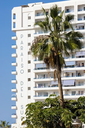 A multi-story hotel with balconies and a palm tree in front. - Playa Paraiso - Exceptional Ocean-sunset View - Pool-wifi-smart TV (Adeje)