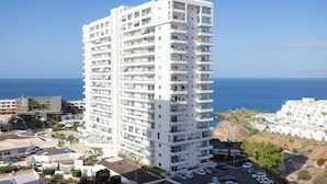 A multi-story hotel with balconies, a parking area, and a view of the sea. - Playa Paraiso - Exceptional Ocean-sunset View - Pool-wifi-smart TV (Adeje)