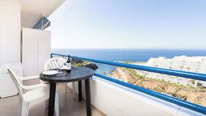 A balcony with a table, chairs, and a view of the sea and buildings. - Playa Paraiso - Exceptional Ocean-sunset View - Pool-wifi-smart TV (Adeje)