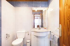 A bathroom with a toilet, sink, mirror, and wooden door. - Playa Paraiso - Exceptional Ocean-sunset View - Pool-wifi-smart TV (Adeje)
