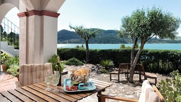 A patio with a table set for a meal, overlooking a lake and hills.
