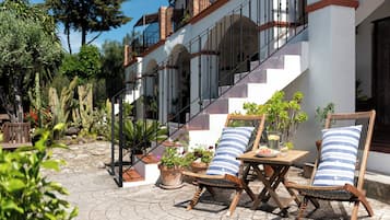 A patio area with outdoor furniture, potted plants, and a staircase leading to an upper level.