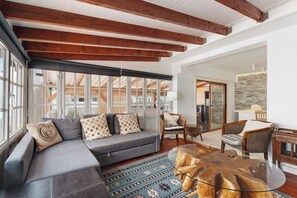 A modern living room with a gray sectional sofa, wooden beams, large windows, and a glass coffee table. - Gran Penthouse Luxury The 307 Parque Royal 1 Wiffi y Jacuzzi (Adeje)