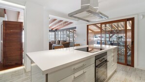 A modern kitchen with a large island, built-in oven, and a view to the outdoor area.