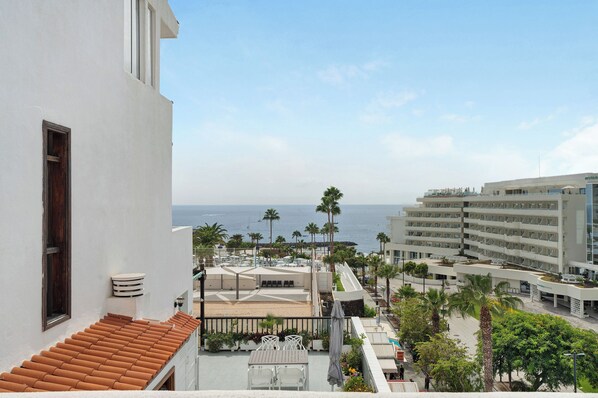 A hotel with a terrace overlooking the sea, featuring a pool, palm trees, and a view of the ocean. - Gran Penthouse Luxury The 307 Parque Royal 1 Wiffi y Jacuzzi (Adeje)