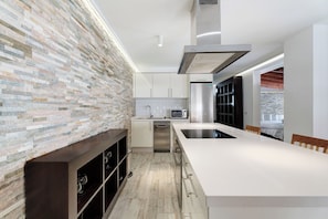 Cozinha moderna com painel de pedra, eletrodomésticos de aço inoxidável e uma ilha grande.