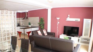 En moderne stue med en sofa, et glasbord og et køkken i baggrunden.
