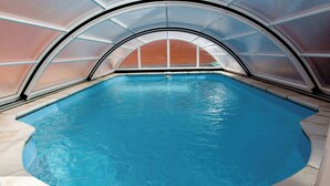 Ein Innenpool mit gewölbter Decke und großen Glaswänden.