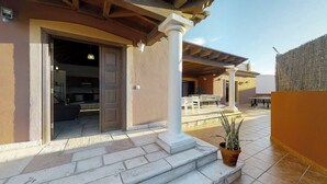 Un área de patio techada con mesa de billar, asientos al aire libre y una planta en maceta.
