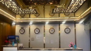 A reception desk with clocks displaying Dubai, Singapore, and London times. - Hotel Royal stay (Thanjavur)