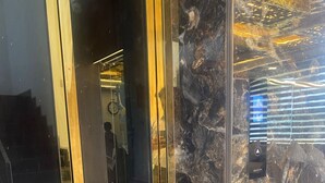 A modern elevator with glass doors and a marble wall. - Hotel Royal stay (Thanjavur)