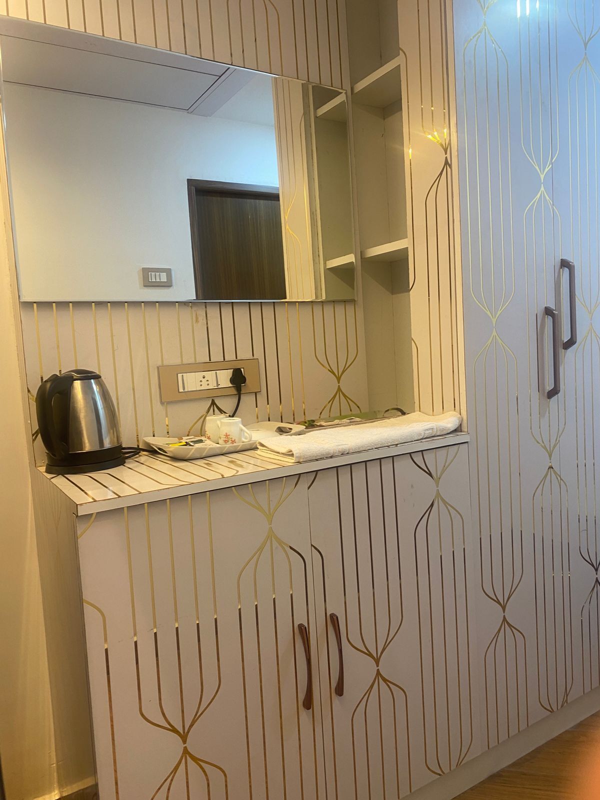 Un baño moderno con un tocador blanco, un espejo, un hervidor de agua y un perchero para toallas.