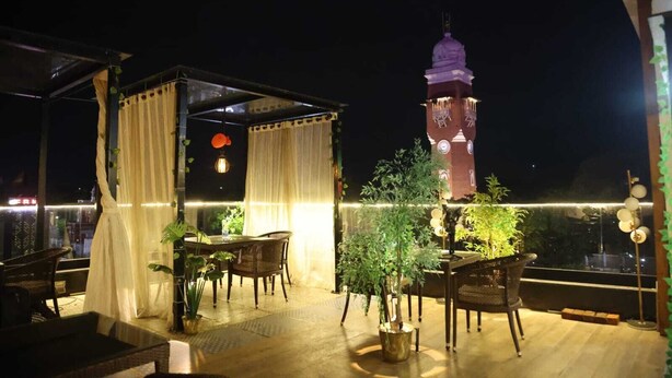 An outdoor seating area with tables and chairs, surrounded by plants and a decorative canopy. - Hotel Royal stay (Thanjavur)
