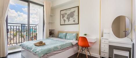 Un dormitorio con cama, escritorio, silla, cómoda, espejo, mapa mundial y balcón con cortinas.