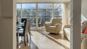 Un balcón amplio con zona de comedor, un sillón cómodo y un sofá.
