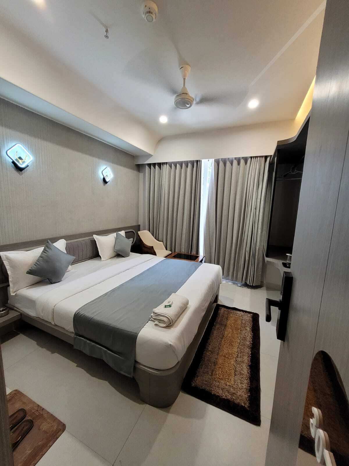 Une chambre d’hôtel moderne avec un grand lit, un bureau, une chaise et une porte de salle de bain.