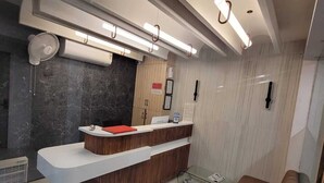 Ein moderner Empfangsbereich mit einer gebogenen Rezeption, einem braunen Sofa und einer Wand aus schwarzem Marmor.