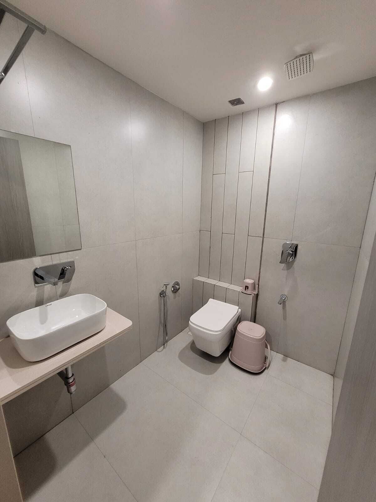 Un baño moderno con un lavamanos, inodoro y bidé blancos, un espejo y una zona de ducha.