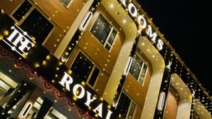Eine Hotelansicht mit beleuchteter Beschilderung für "The Royal Era Restaurant" und "Maniac Mobiles" darunter.