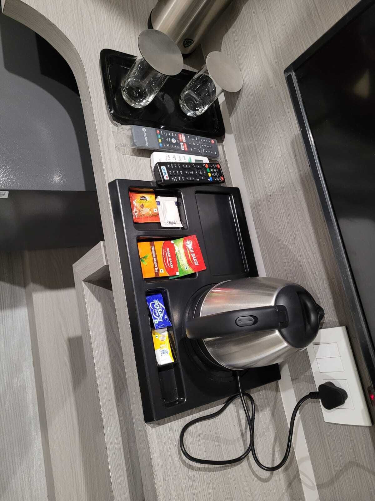 Una kitchenette con cafetera, sobrecitos de azúcar, un control remoto y un microondas.