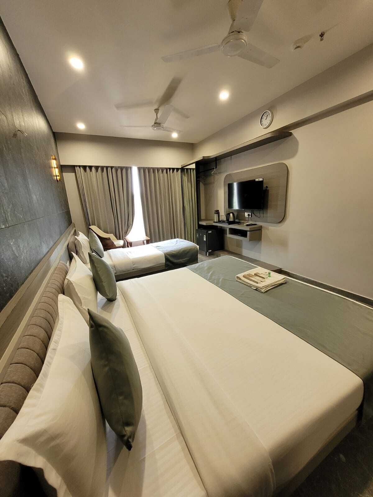 A hotel room with a large bed, a TV, and a ceiling fan.