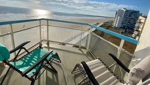 Un balcon avec vue sur la plage et les bâtiments.