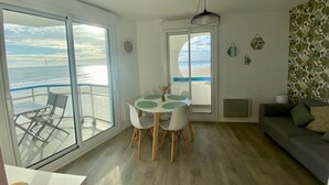 Une pièce comprenant une table et des chaises, un canapé et une grande fenêtre donnant sur l’océan.