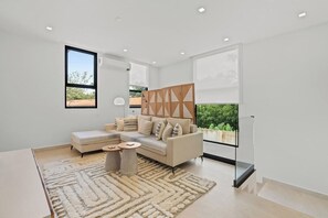 A modern living room with a sofa, a coffee table, and a large window.