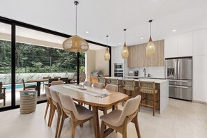 Una cocina moderna con comedor, ventanas amplias y vistas a una piscina.