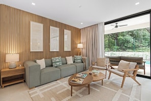 A modern living room with a sofa, armchairs, a coffee table, and a large window with a view of greenery.