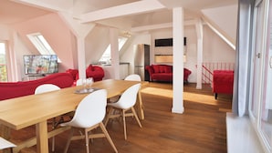 Un loft amplio con comedor, sofás rojos y cocina.