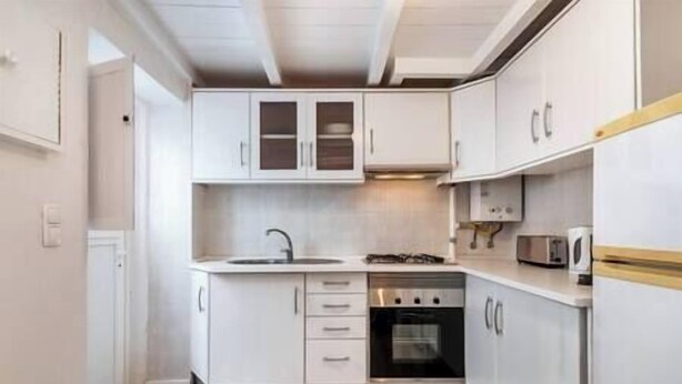 A compact kitchen with white cabinets, a built-in oven, a microwave, and a sink.