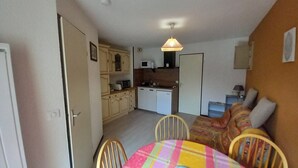 A compact living space with a dining area, kitchenette, and a sofa. - Cozy T2 near slopes with parking and balcony (Le Lioran)