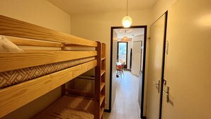 A room with a bunk bed, a hallway leading to a dining area, and a door with a lock. - Cozy T2 near slopes with parking and balcony (Le Lioran)