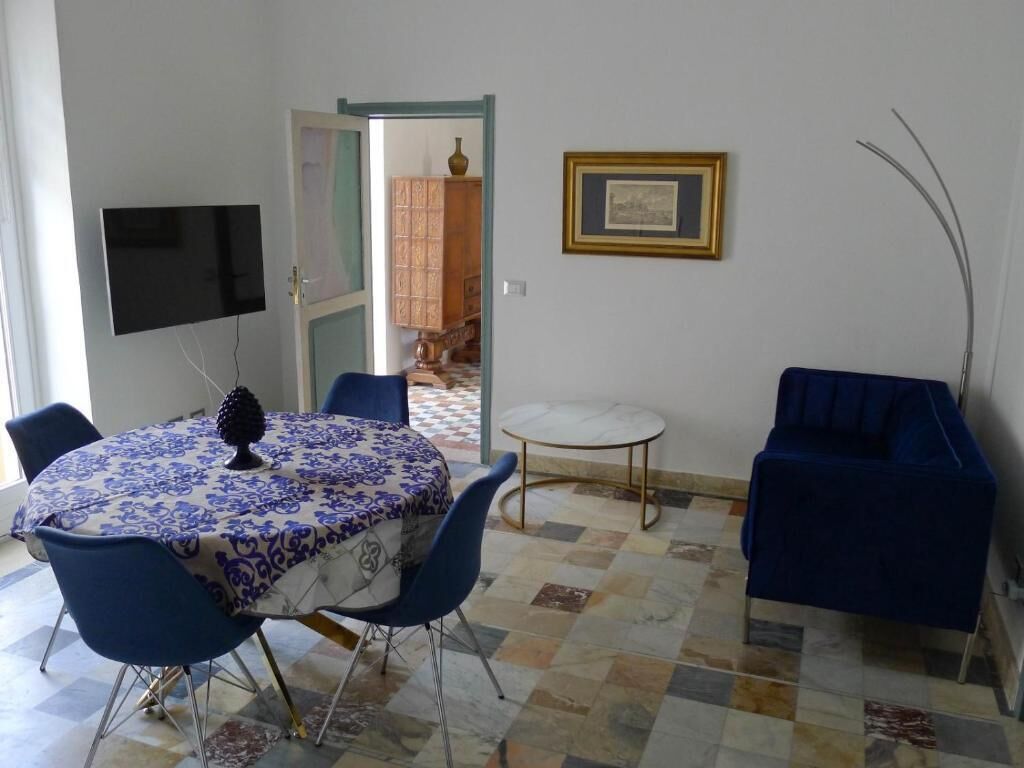 Un coin repas comprenant une table ronde, des chaises bleues, une petite table ronde et un canapé bleu.